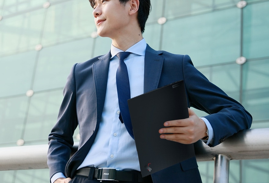 Person carrying ultraportable Lenovo ThinkPad X1 Carbon Gen 10 laptop under their arm