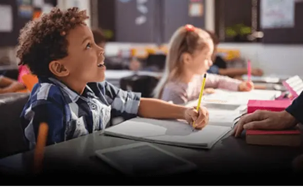 Young boy and girl working at classroom desks 