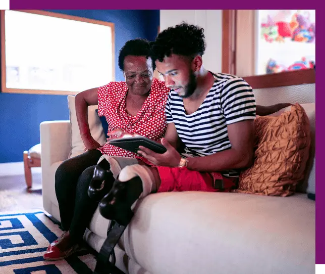 A man/father supervising a teen boy who is taking notes while looking at a Lenovo laptop